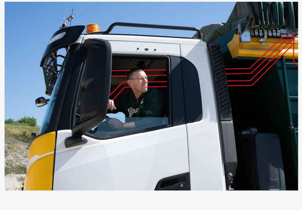 Operator leaning out of the cab while the body is tipping, with ITA EVO monitoring the cycle